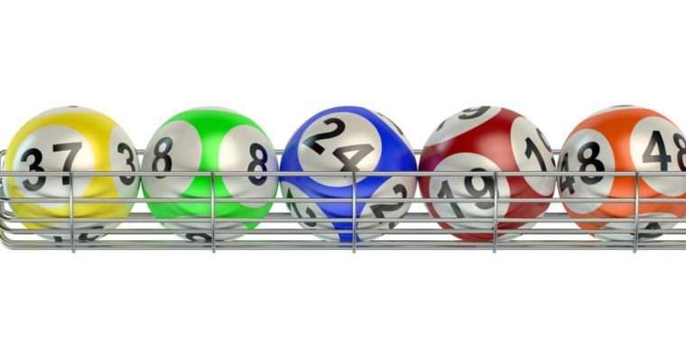 Yellow, Green, Blue, Red and Orange Numbered Lottery Balls Sit on Silver Metal Rack