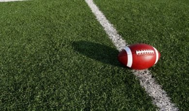 Sun Casts a Shadow of Football on Grassy American Football Field