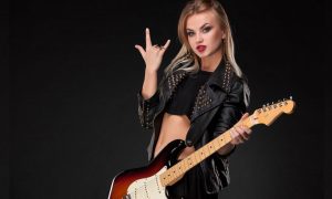 Young Woman in Studded Black Leather Jacket Holds Electric Guitar