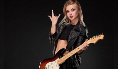 Young Woman in Studded Black Leather Jacket Holds Electric Guitar