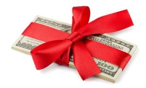 Red Ribbon Wraps a Stack of American $100 Banknotes on White Background