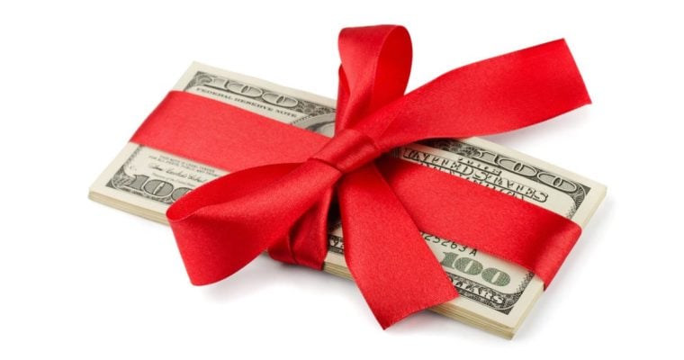Red Ribbon Wraps a Stack of American $100 Banknotes on White Background