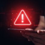 Red Digital Warning Sign Displayed over Tablet Held By Man in Black T-Shirt