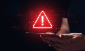 Red Digital Warning Sign Displayed over Tablet Held By Man in Black T-Shirt