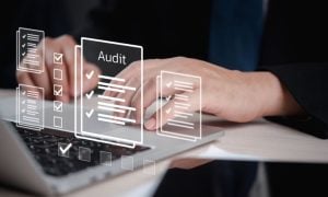 Man Uses Laptop with Digital Image Overlay of Papers with Audit Checks