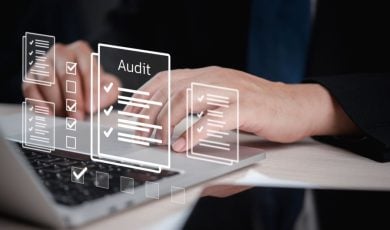 Man Uses Laptop with Digital Image Overlay of Papers with Audit Checks