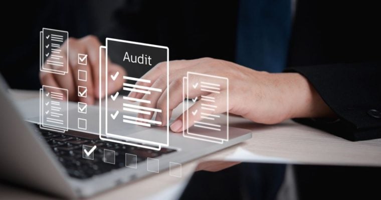 Man Uses Laptop with Digital Image Overlay of Papers with Audit Checks