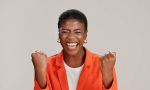 Happy Black Woman Smiling with Eyes Closed in Orange Jacket