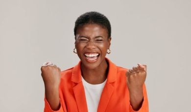 Happy Black Woman Smiling with Eyes Closed in Orange Jacket
