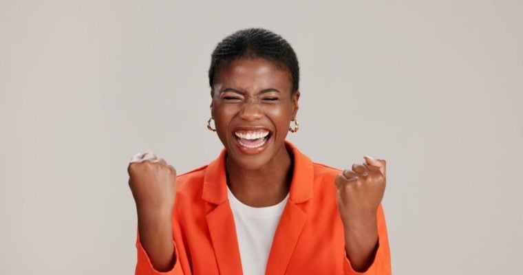Happy Black Woman Smiling with Eyes Closed in Orange Jacket