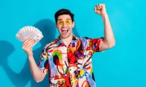 Man with Yellow Glasses and Colorful Shirt Hold Fanned Cash with Happy Expression