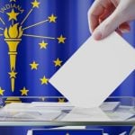 Hand Drops White Envelope Into Clear Box with Indiana State Flag Background