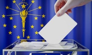 Hand Drops White Envelope Into Clear Box with Indiana State Flag Background