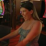 Excited Woman Sitting in Front Of Slot Game Inside Casino