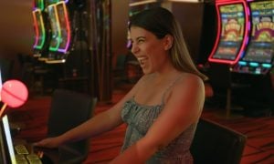 Excited Woman Sitting in Front Of Slot Game Inside Casino