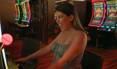 Excited Woman Sitting in Front Of Slot Game Inside Casino