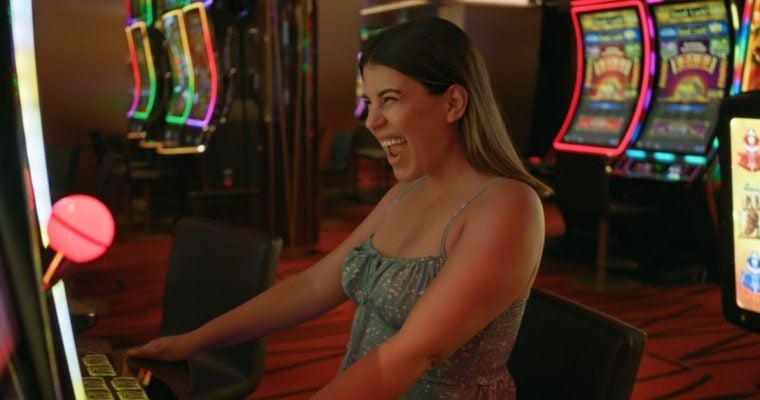 Excited Woman Sitting in Front Of Slot Game Inside Casino