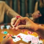 Three People Playing Poker with Foreground Image Closeup of Man Balancing Poker Chip on Hand