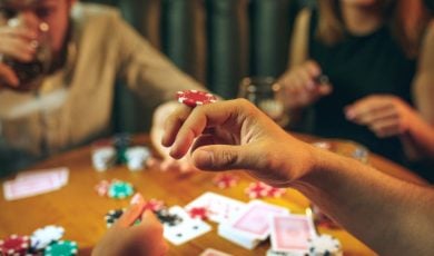 Three People Playing Poker with Foreground Image Closeup of Man Balancing Poker Chip on Hand