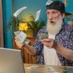 Older Man Stares at Laptop in Shock with Cash Falling From Sky Around Him