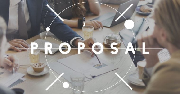 Team of Developers Sit at A Table Discussing Plans with Text Proposal Written Over Image