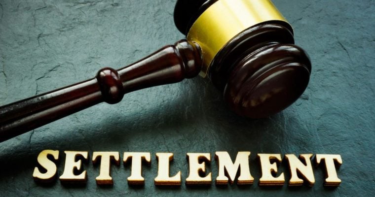 Judge's Wooden Gavel with Gold Trim Sits on Green Desk Above the Word Settlement