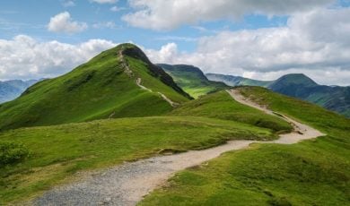 Grassy Mountain With Clear Path and Cloudy Skies