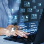 Digital Icons of Personal Profiles Displayed In Front of Laptop While Woman Reviews Them