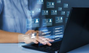 Digital Icons of Personal Profiles Displayed In Front of Laptop While Woman Reviews Them