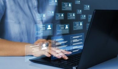 Digital Icons of Personal Profiles Displayed In Front of Laptop While Woman Reviews Them