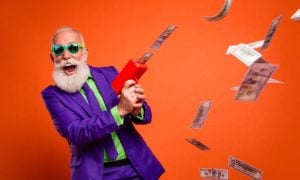 Man In Purple and Green Suit with Happy Expression Uses Money Rain Machine to Make Cash Fall from Air