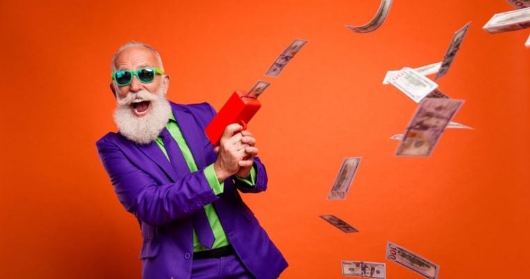 Man In Purple and Green Suit with Happy Expression Uses Money Rain Machine to Make Cash Fall from Air
