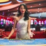 Dark-haired Asian Card Dealer Stands Behind Blackjack Table Inside Casino