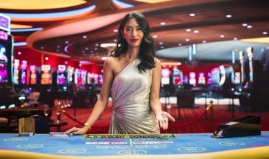 Dark-haired Asian Card Dealer Stands Behind Blackjack Table Inside Casino