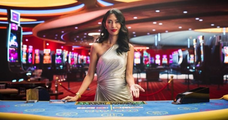 Dark-haired Asian Card Dealer Stands Behind Blackjack Table Inside Casino