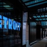 Commercial Building with Blue Neon Detroit Sign and People Walking Around at Sunset in Michigan