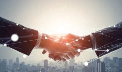 Two Businessmen Shake Hands Above City Skyline with Geolocation Dots Overlay