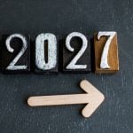 Wooden Blocks with 2027 in White Ink on Black Background with Arrow Pointing Right Below