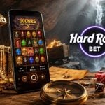 Cave Filled With Treasure, Cell Phone with Goonies Online Slot and Hard Rock Bet Logo