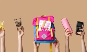 Back-To-School Supplies Like Pink Backpack, Scissors and Pencil Case Held Up By Hands on Solid Background