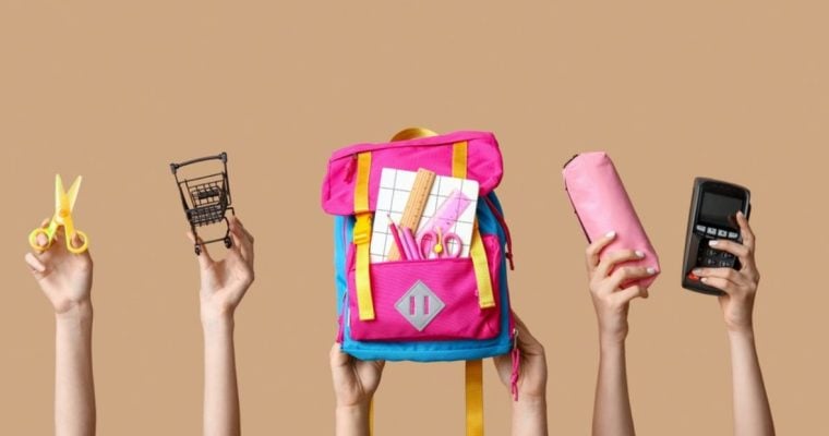 Back-To-School Supplies Like Pink Backpack, Scissors and Pencil Case Held Up By Hands on Solid Background