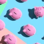One Piggy Bank Faces Viewer While Others Face Left On Colored Flat Background