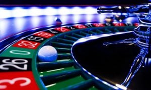 Close Up Image of Lit Roulette Wheel with White Ball Landed on Green 0