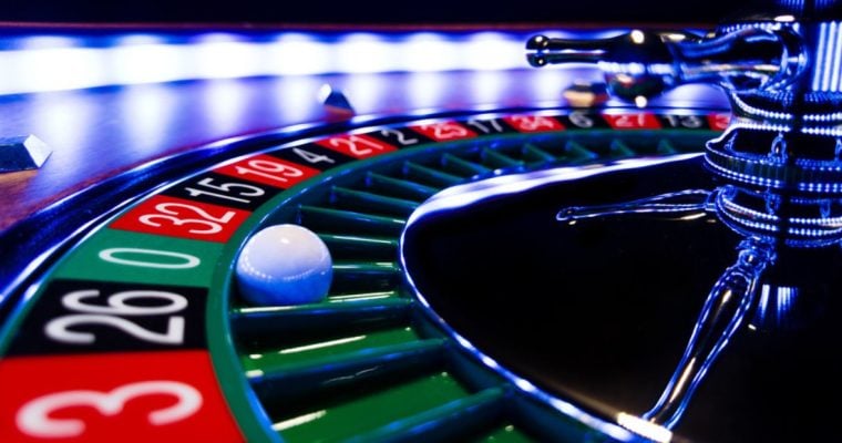 Close Up Image of Lit Roulette Wheel with White Ball Landed on Green 0
