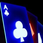 Blue Neon-Lit Ace of Clubs Playing Card Sits In Front of 3 Others