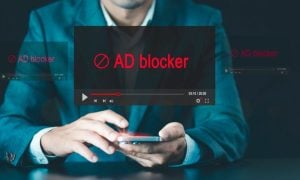 Man In Suit Holds Cell Phone with Digital Image Overlay Of Ad Blocker in Red Font