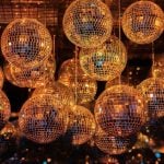 Disco Balls With Metallic Gold Glow Hang from Ceiling in Dark Background