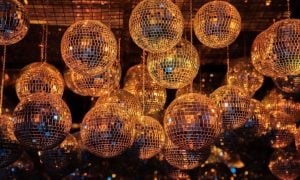 Disco Balls With Metallic Gold Glow Hang from Ceiling in Dark Background