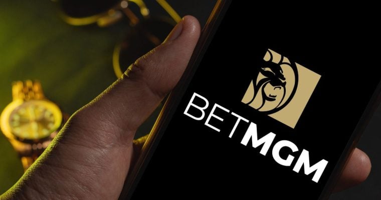 Men's Sunglasses and Gold Watch in Background to Man Holding Cell Phone with BetMGM Logo