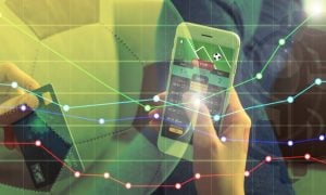 Man Holds Cell Phone With Sports Betting App and Finacial Line Graph Image Overlay